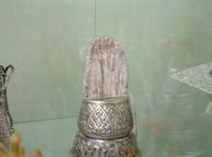 In the backgound a carved Sandelwood Buddah flanked By two white bull elephant Tusks, various silver urns and Chalices.